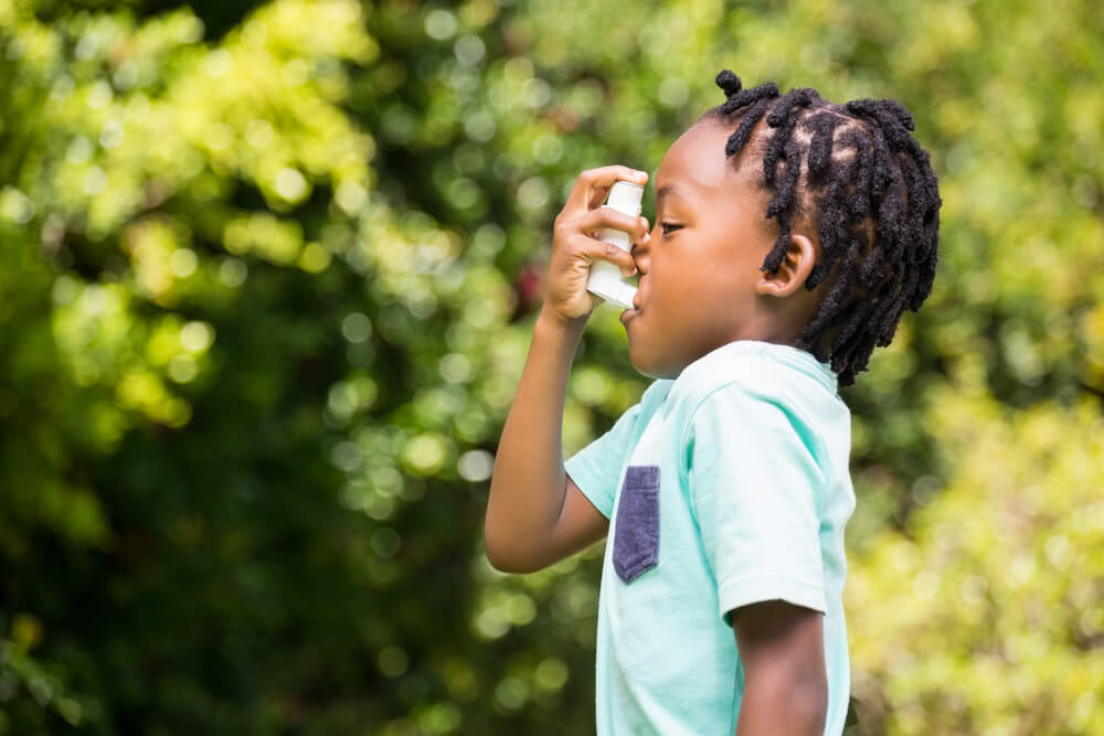 Boy using an asthma inhaler in the park